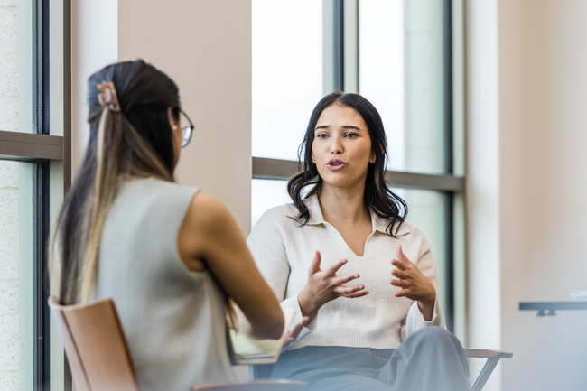 Zwei Frauen sitzen in einem Büro und sprechen miteinander