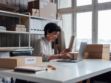 Person sitzt an einem Arbeitsplatz mit Computer und Akten